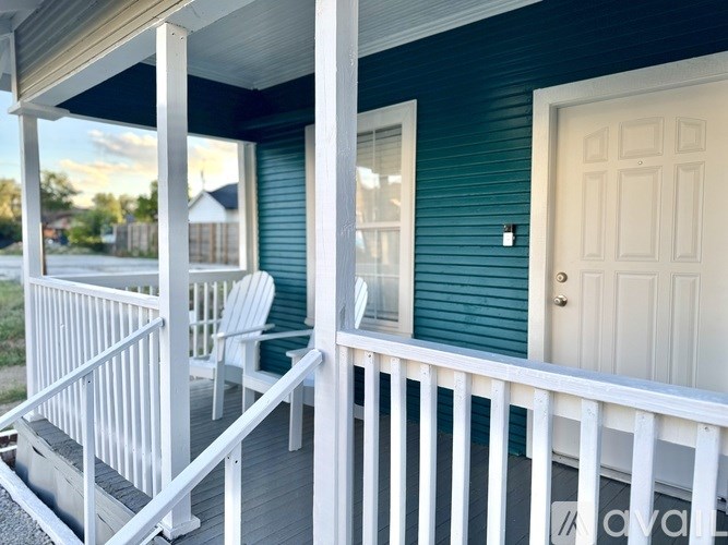 A porch with a white railing and a white door.