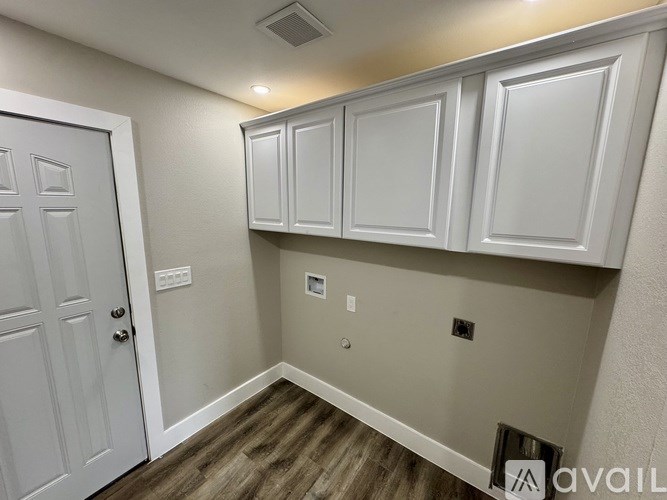 A kitchen area with white cabinets and a door on the left.