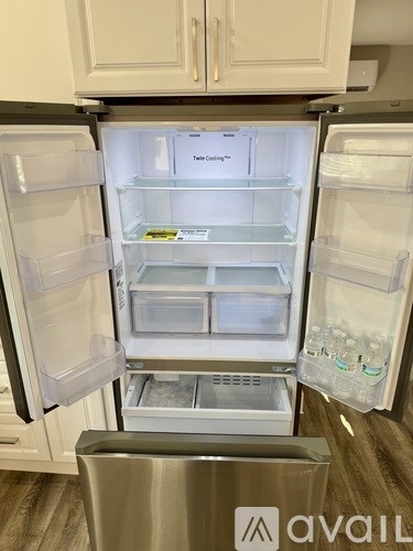 A white refrigerator with its door open and a trash can in front of it.