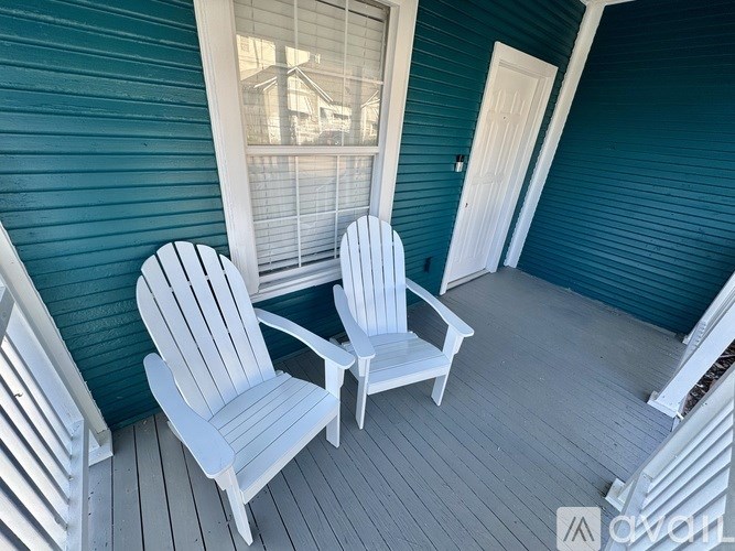 Two white chairs on a porch.