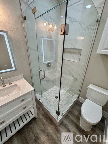 A bathroom with a glass shower enclosure and a white toilet.