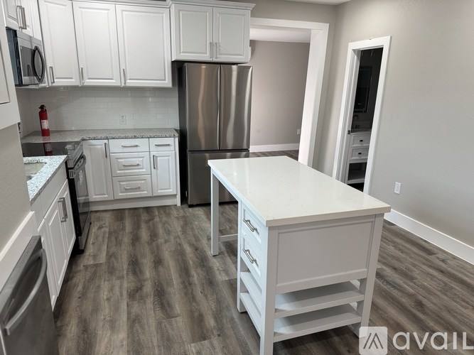 A kitchen with white cabinets and a stainless steel refrigerator.