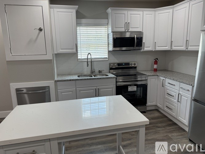 A white kitchen with a table in the middle.