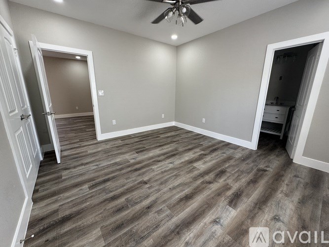 A room with a ceiling fan and wood flooring.