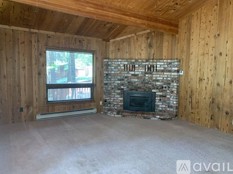 A room with wooden walls and a stone fireplace.
