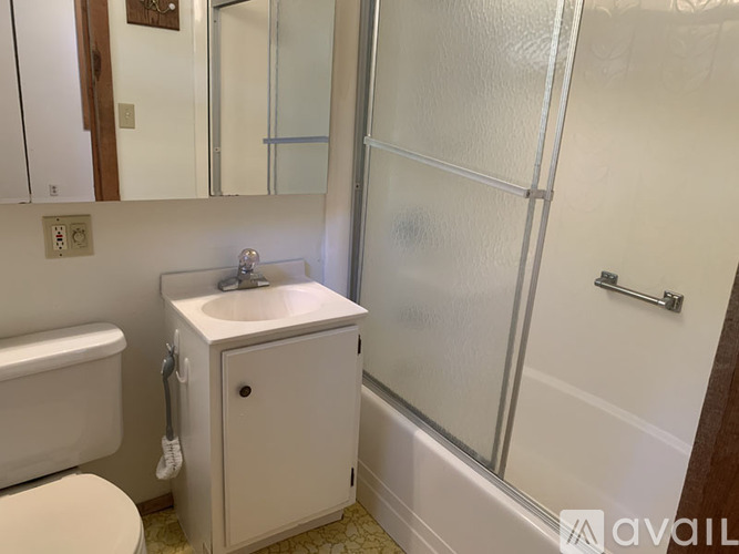 A white bathroom with a toilet, sink, and shower.