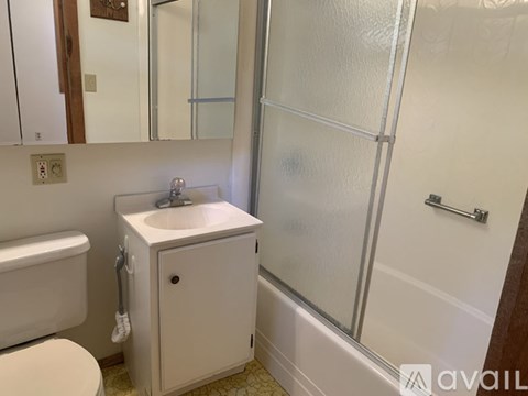 A white bathroom with a toilet, sink, and shower.