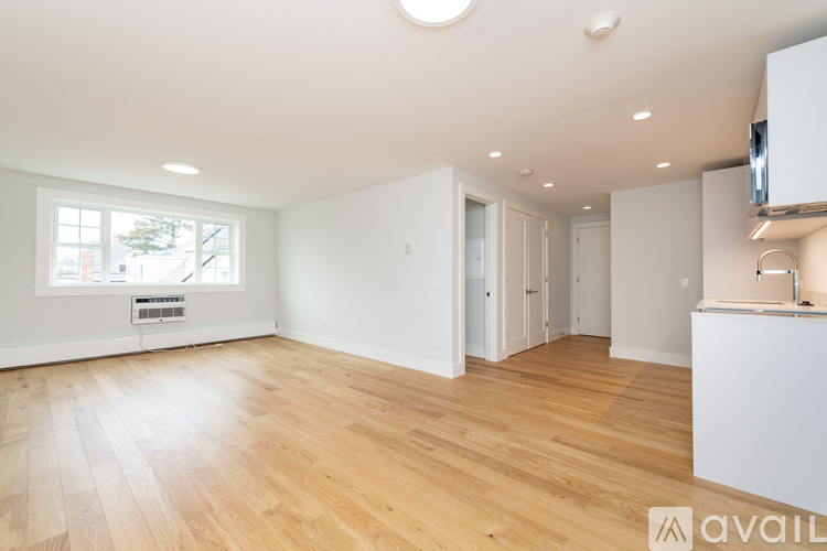 A spacious room with wooden flooring and white walls.