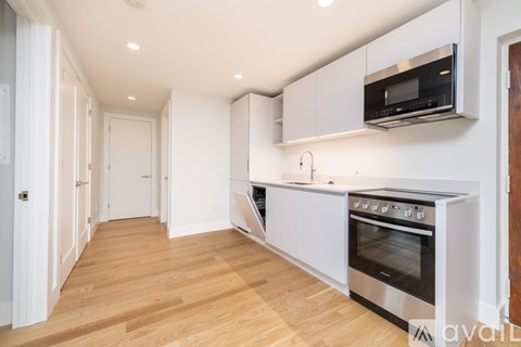 A modern kitchen with wooden floors and stainless steel appliances.