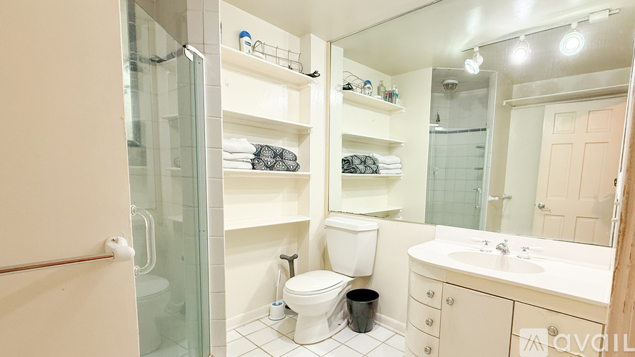 A bathroom with a glass shower door, a toilet, a sink, and a mirror.