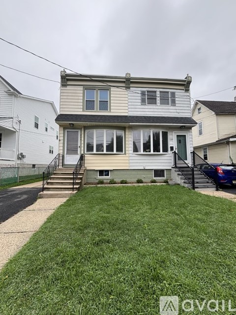 A two-story house with a front yard and a car parked in the driveway.