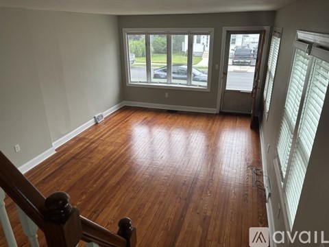 A room with wooden floors and a staircase leading to the next level.
