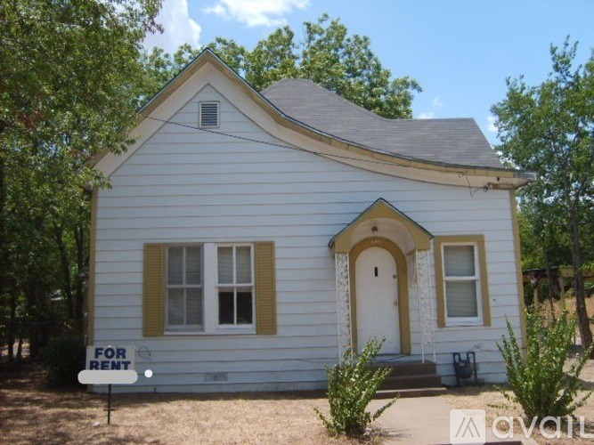 A small white house with a yellow trim is for rent.