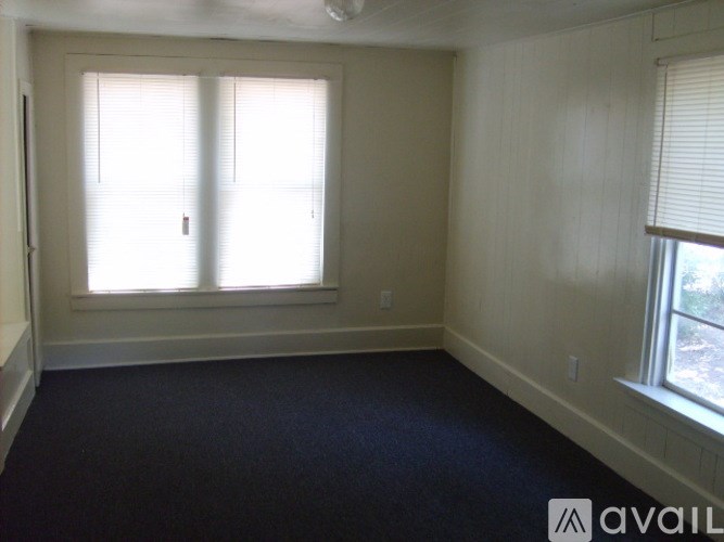 A room with a carpeted floor and two windows.