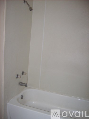 A white bathtub with a shower head attached to the wall.