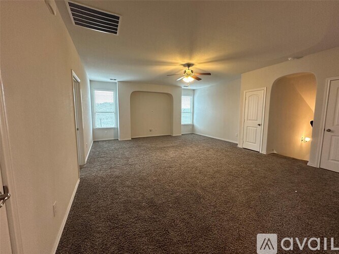 A spacious room with a ceiling fan and carpeted floor.