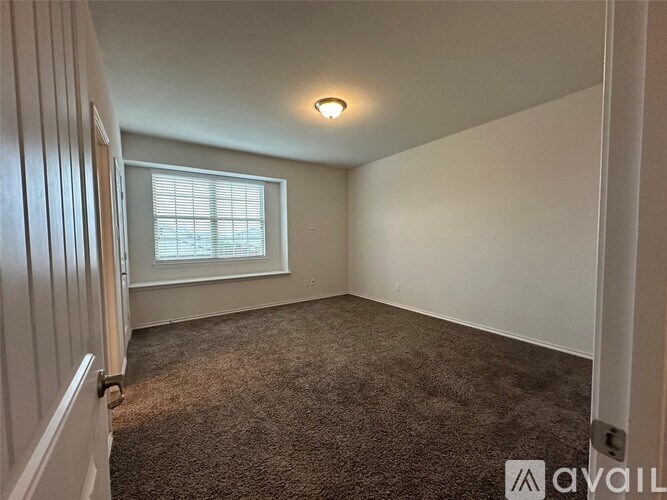 A room with a carpeted floor and a window with blinds.