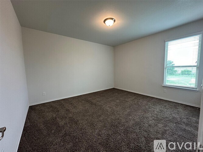 A room with a carpeted floor and a window with blinds.