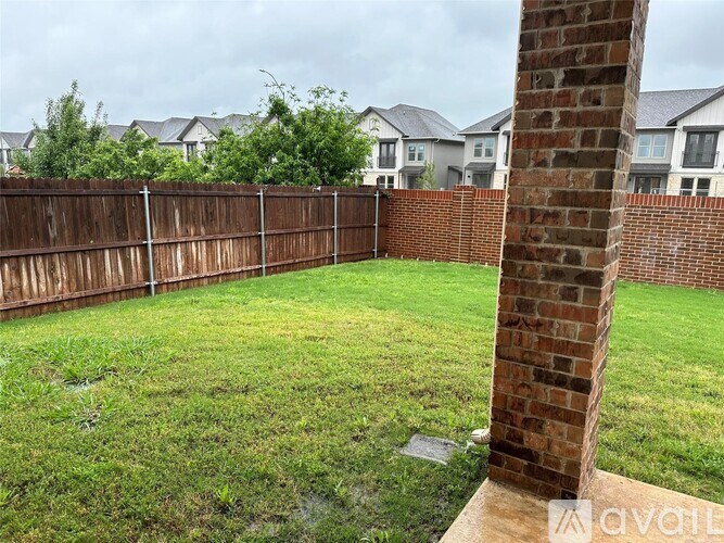 A backyard with a wooden fence and a brick pillar.