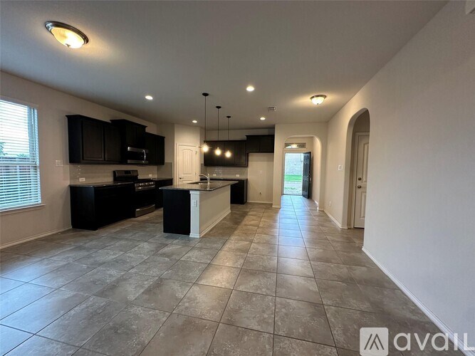 A spacious kitchen with black cabinets and a central island.