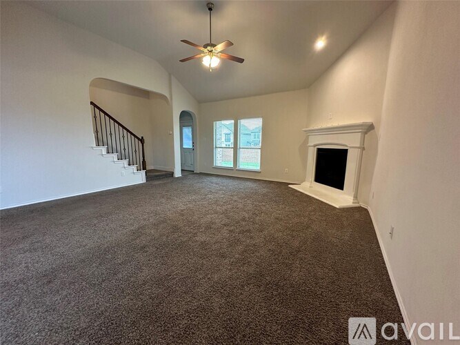 A living room with a carpeted floor and a ceiling fan.