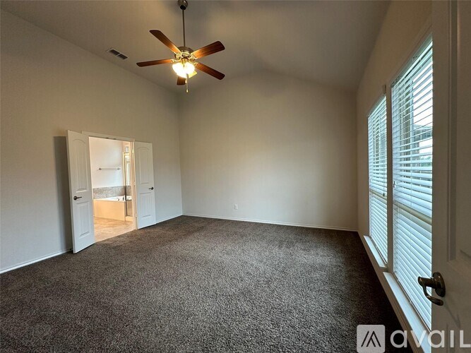 A room with a ceiling fan and carpeted floor.