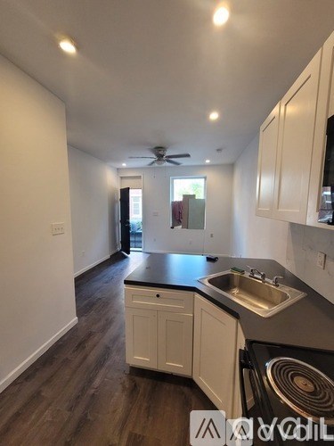 A kitchen with white cabinets and a black countertop.