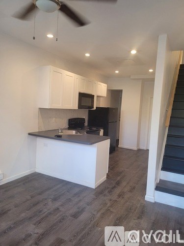 A kitchen with a black countertop and white cabinets.