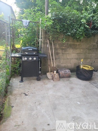 A black grill is on a patio next to a bag and a hose.
