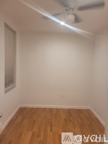 A room with a ceiling fan and wooden flooring.
