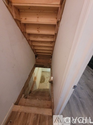 A wooden staircase with a white wall on one side.