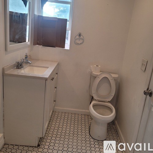 A white toilet sits in a bathroom with a sink and mirror.
