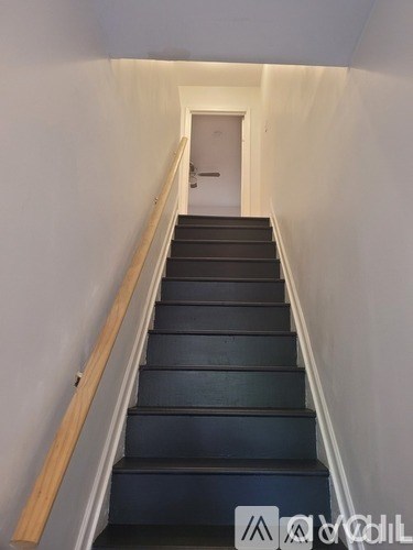 A staircase with black steps and wooden handrails.