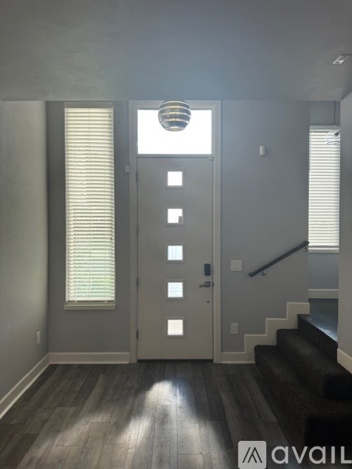 A hallway with a staircase and a door with a window above it.