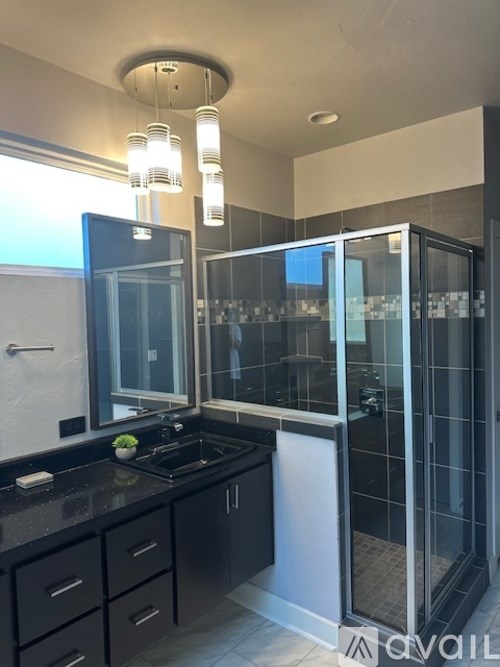A modern kitchen with black countertops and a glass-enclosed shower.