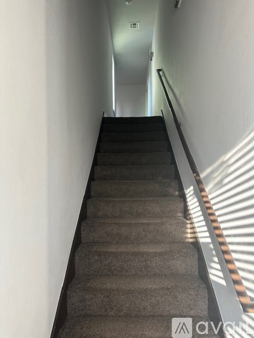 A staircase with a carpeted runner and a metal handrail.