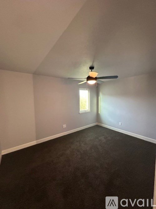 A room with a ceiling fan and a window.