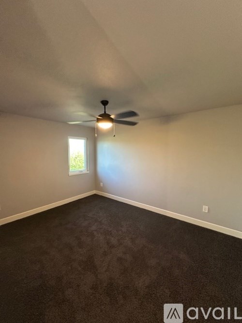 A room with a ceiling fan and a window.