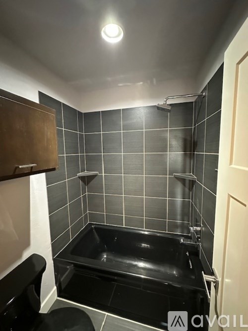 A small black bathtub in a bathroom with black tiles.