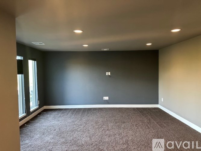 A room with carpeted floor and a window on the left side.