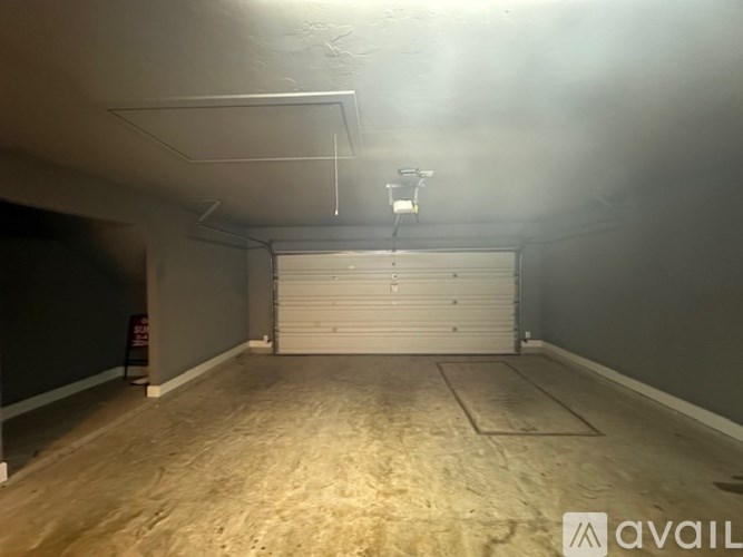 A spacious garage with a white roller shutter door and a wooden floor.