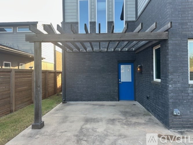 A house with a blue door and a wooden pergola.