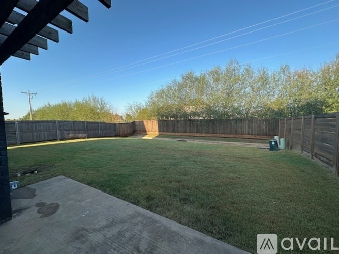 A backyard with a wooden fence and a concrete patio.