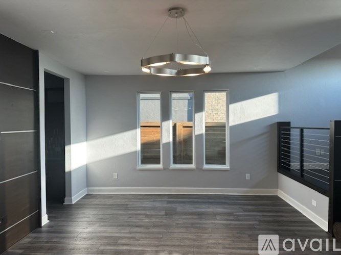 A spacious room with a dark wood floor and a large window with a view of a building outside.