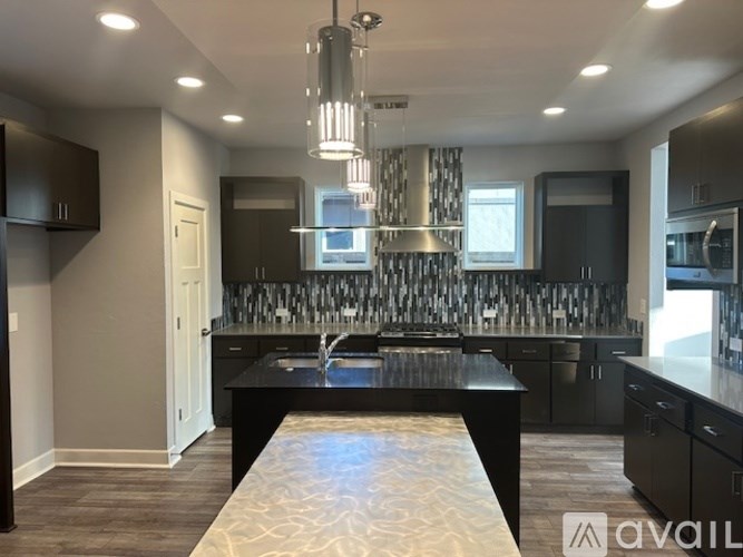 A modern kitchen with a black countertop and a patterned backsplash.