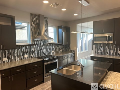 A modern kitchen with dark wood cabinets and a black countertop.
