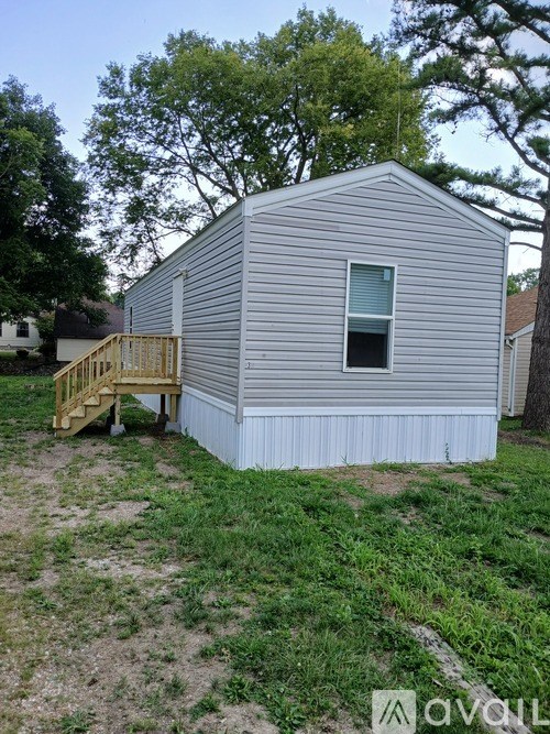 A small grey house with a wooden staircase leading to the door.