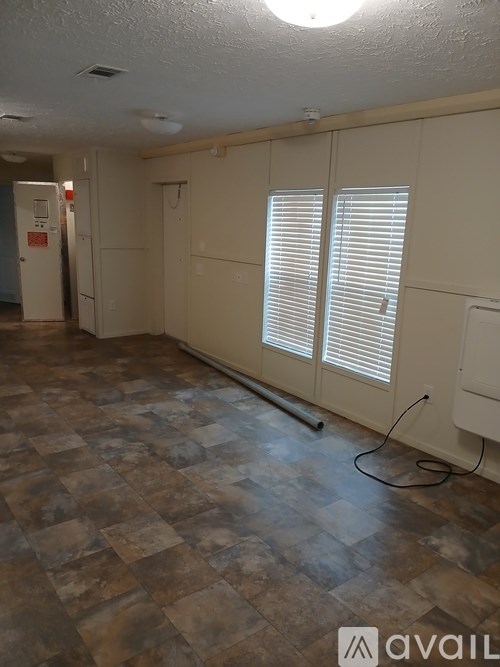 A room with a tiled floor and a window with blinds.