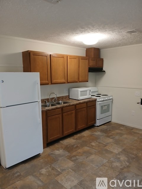 A kitchen with a white refrigerator, microwave, and oven.