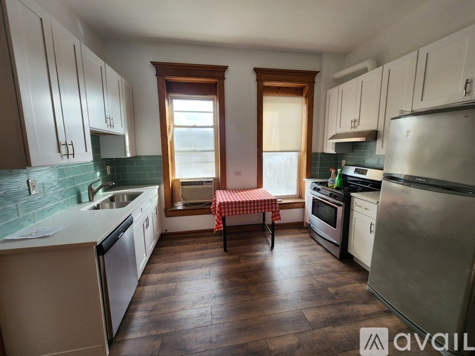 A kitchen with wooden floors and white cabinets.